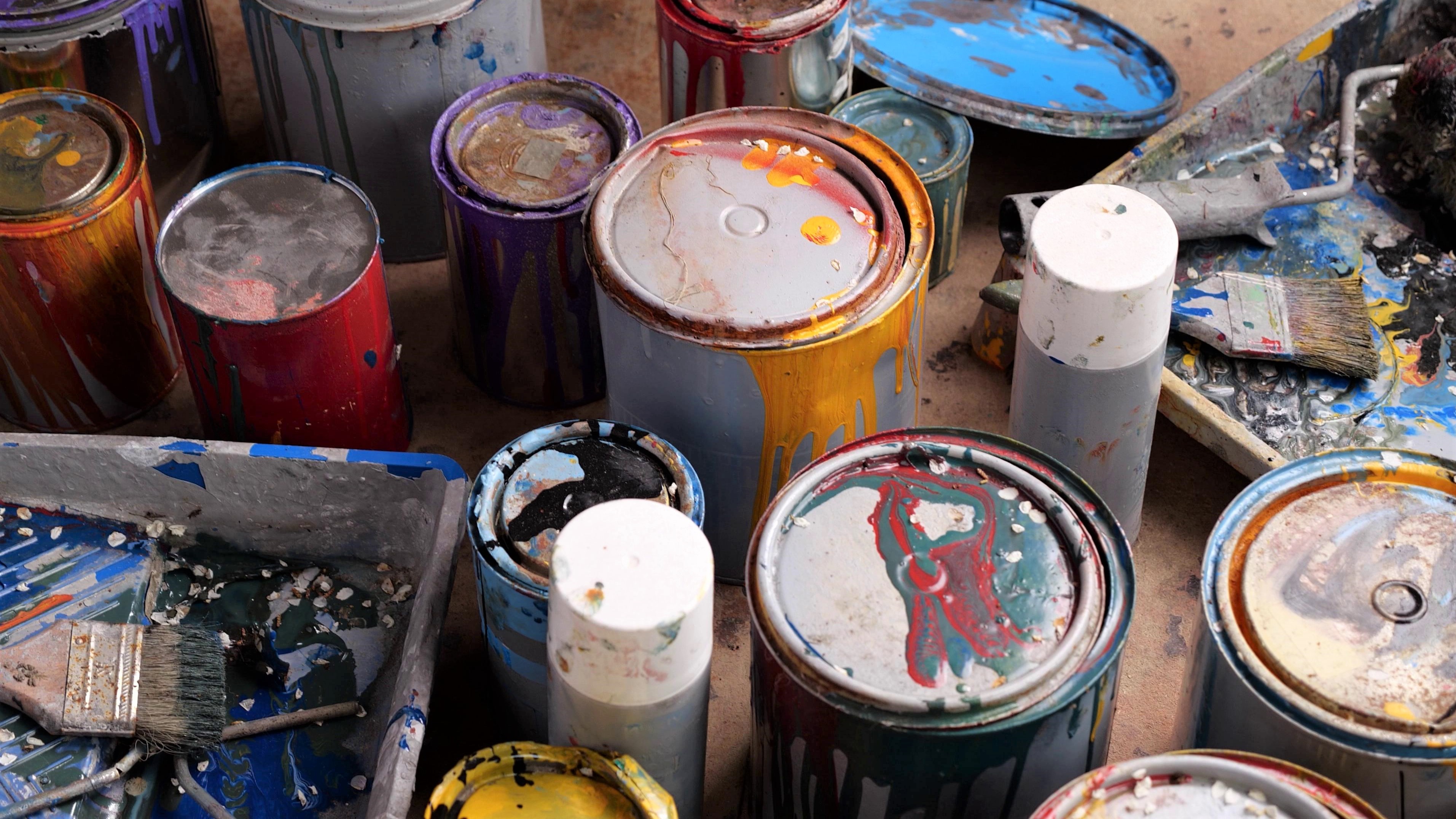 An image of paint cans that cannot be disposed of in a Dumpster Dudez of Omaha dumpster - for more information on household hazardous waste disposal, contact Dumpster Dudez 