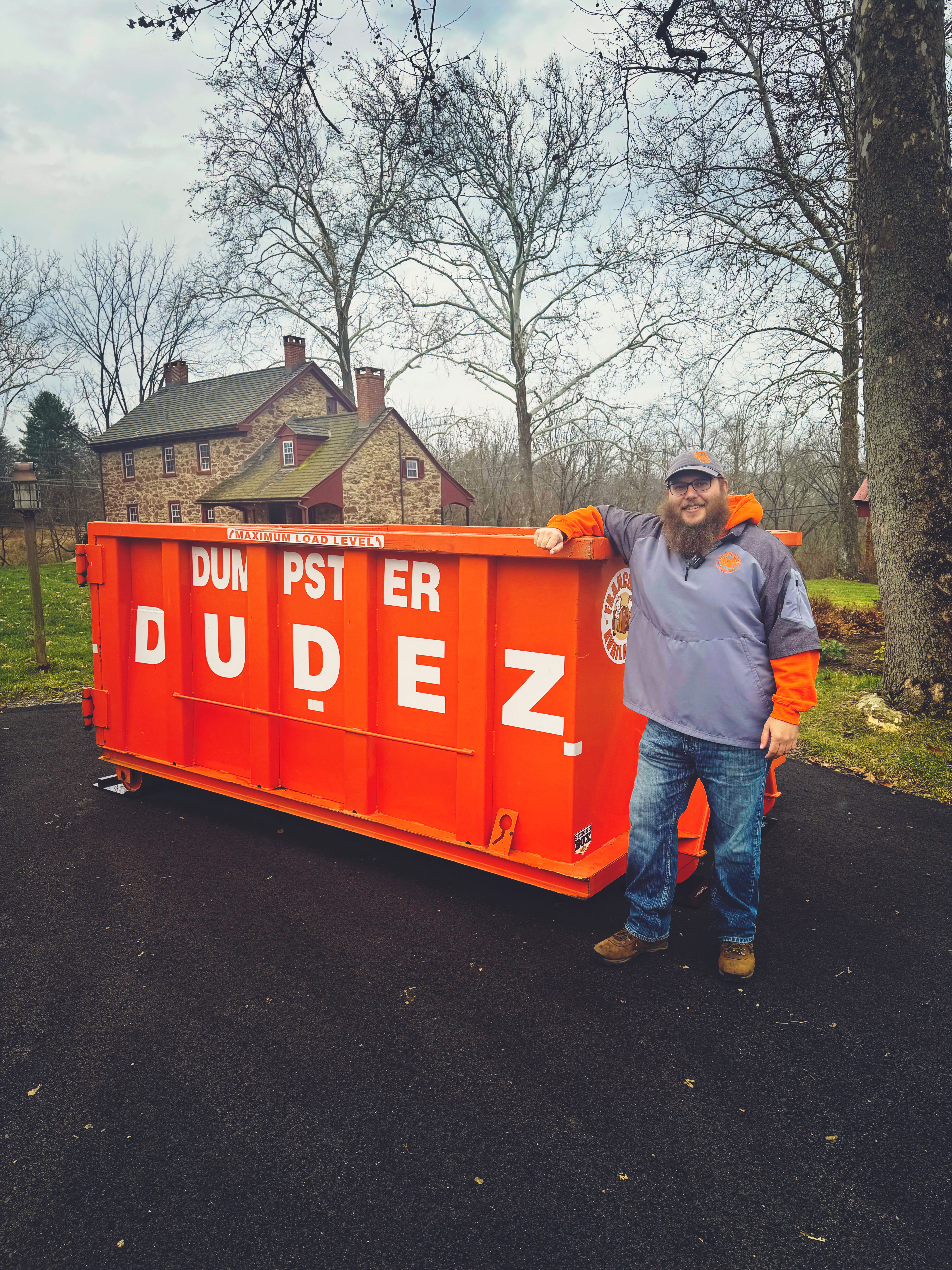 A Dumpster Dudez employee standing next to one of our 10 yard dumpsters.