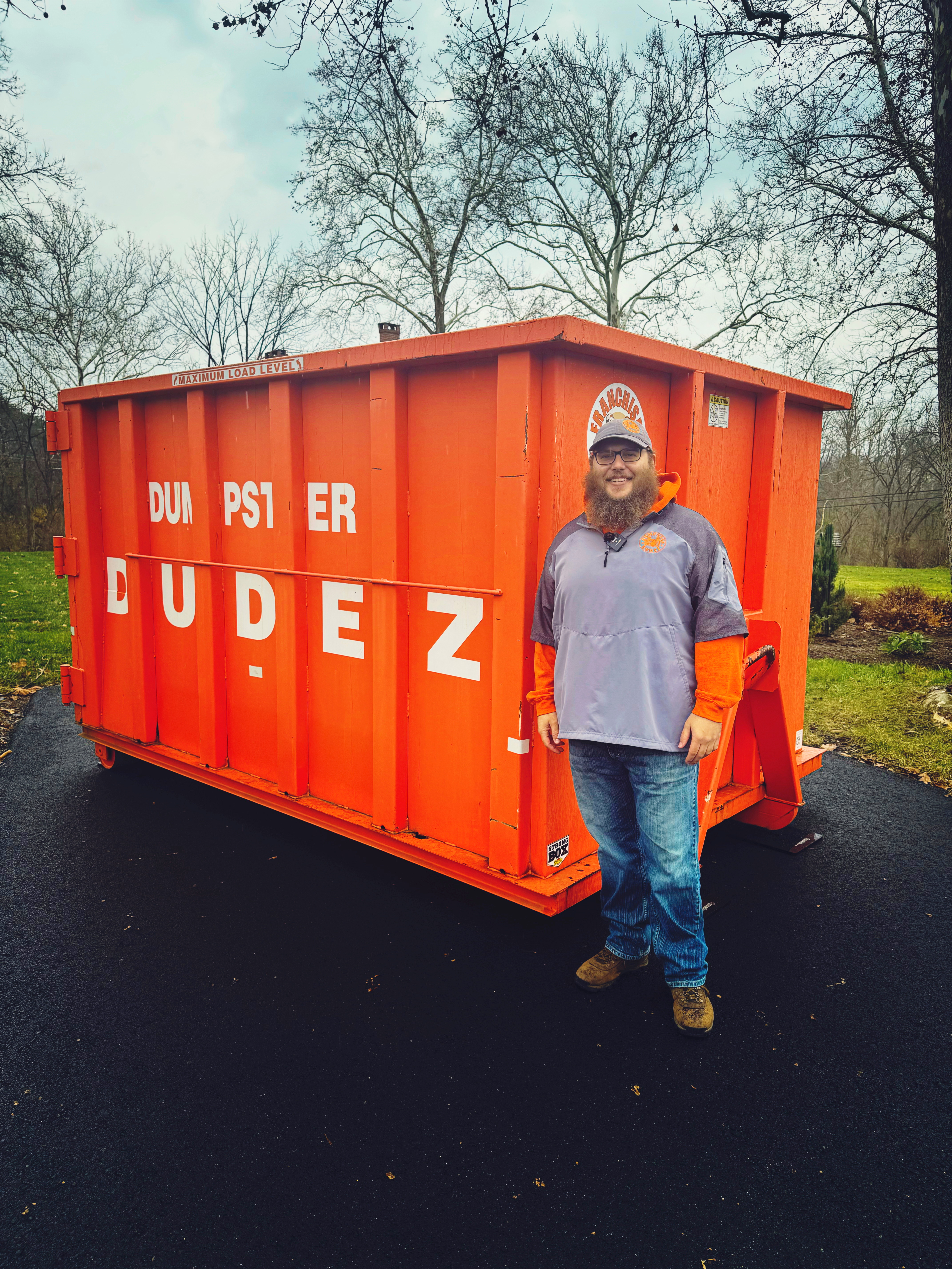A Dumpster Dudez employee standing next to one of our 20 yard dumpsters.