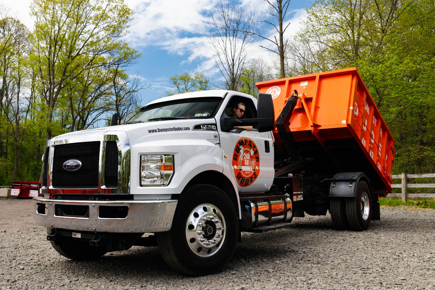 An Dumpster Dudez truck with a roll-off dumpster for easy Fayetteville–Springdale–Rogers refuse pickup services.