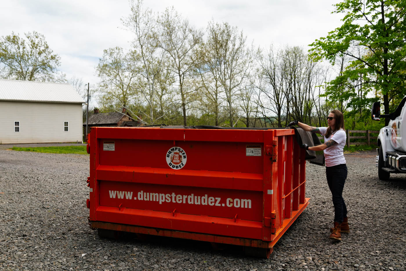 Dumpster Dudez driver disposing waste in one of our dumpsters - contact us for reliable and hassle free services.