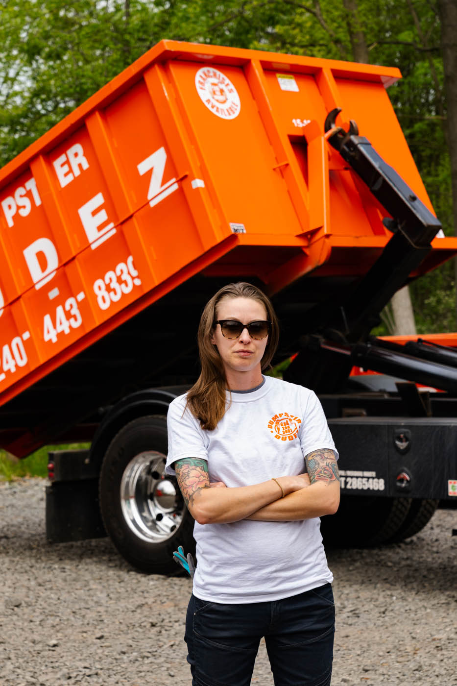 A Dumpster Dudez team member standing in front of a company dumpster, contact Dumpster Dudez one of the best dumpster rental companies in Minneapolis, MN.