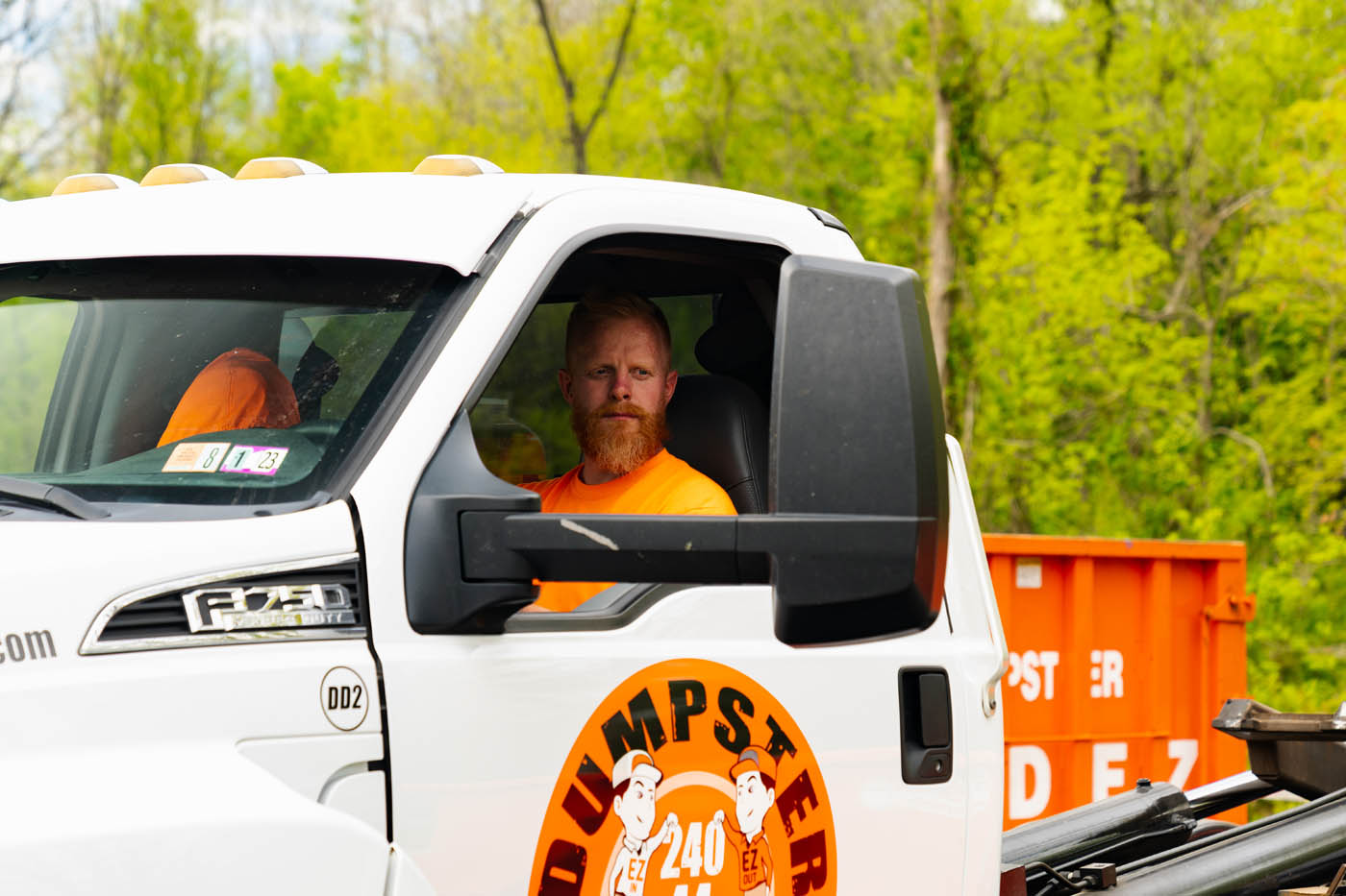 A Dumpster Dudez employee driving a truck - reserve a dumpster today!