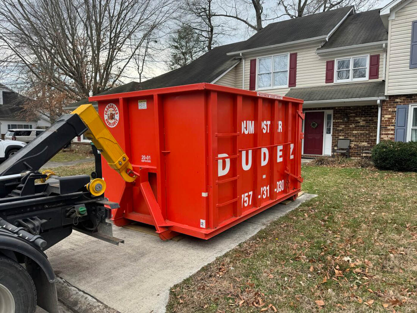 
				A roll-off dumpster from Dumpster Dudez parked in a home's driveway.
			