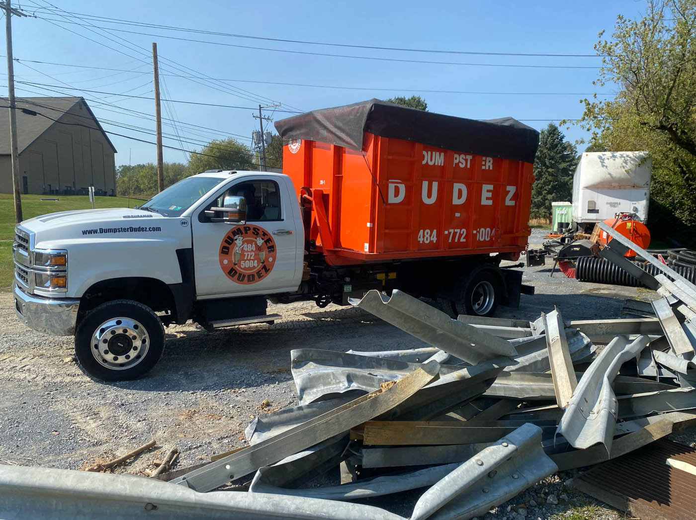 
				A Dumpster Dudez truck and dumpster in front of a large pile of debris, ready to make a large waste management project easy.
			
