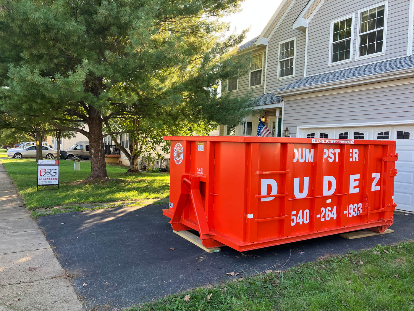 Dumpster Dudez rental dumpster in front of a home - learn how to streamline your moving with our rental services!