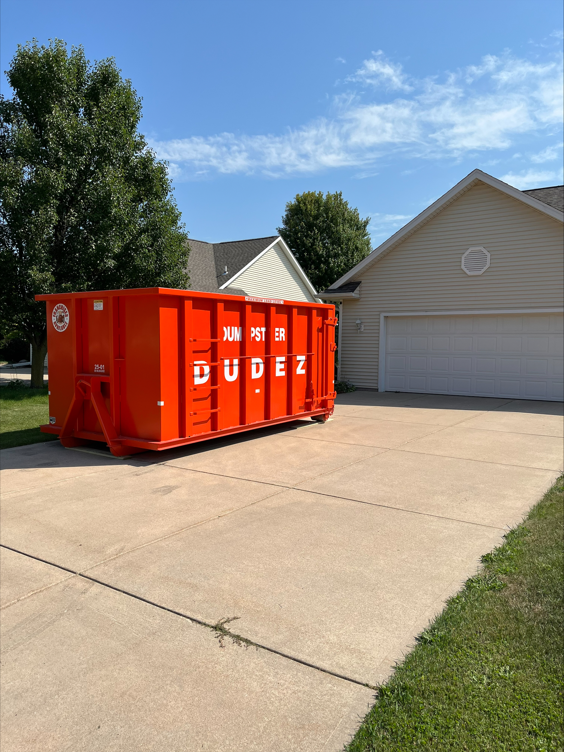 A Dumpster Dudez  dumpster parked in a driveway for use to throw furniture away.