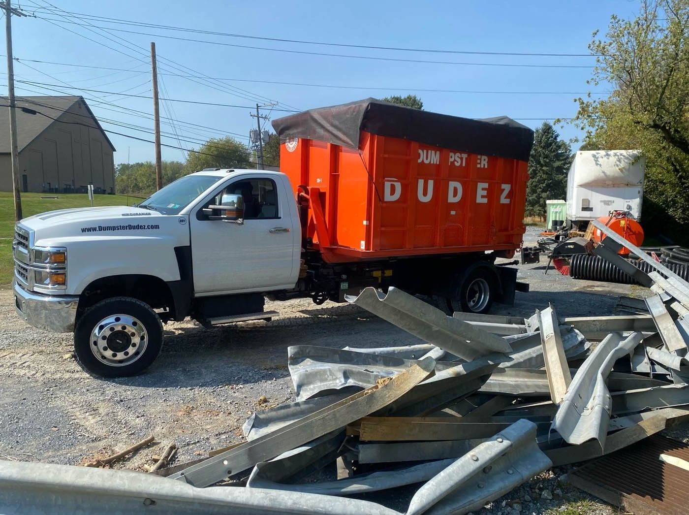 A Dumpster Dudez dumpster parked in front of bulky construction debris - contact us today to rent a Omaha bulky item pickup container.